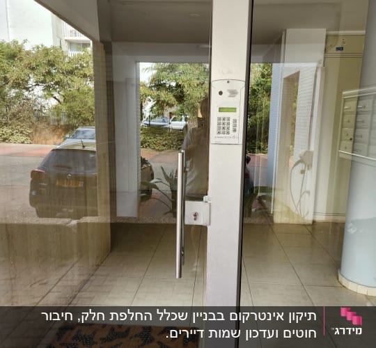 אינטרקום עם לוח מקשים ליד דלת זכוכית